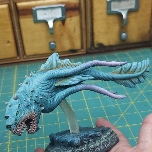 a hand is holding a blue dragon figurine